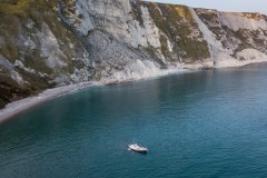 Aerial view of Mupe Bay at sunrise with a lone yacht, Dorset, U.K.